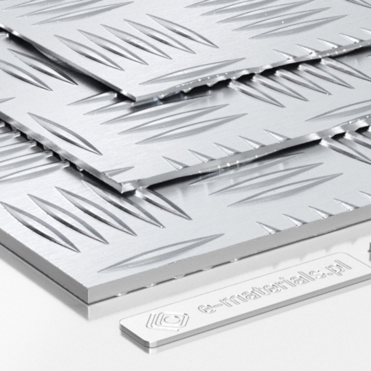 Kilka warstw aluminiowych blach ryflowanych z wzorem łezek ułożonych na białym tle