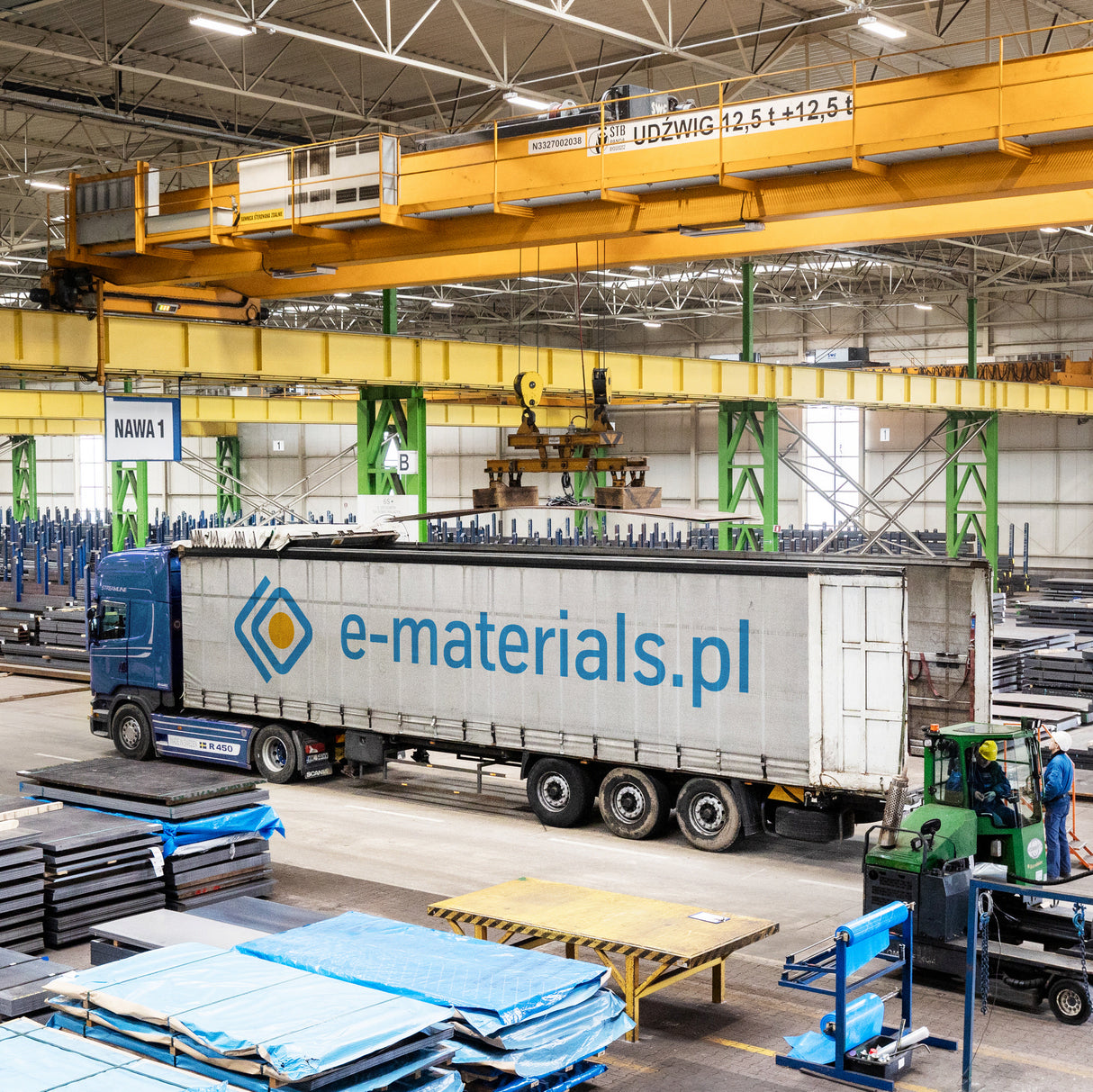 Wnętrze magazynu e-materials.pl z widocznym logo na naczepie ciężarówki gotowej do załadunku i wysyłki materiałów.