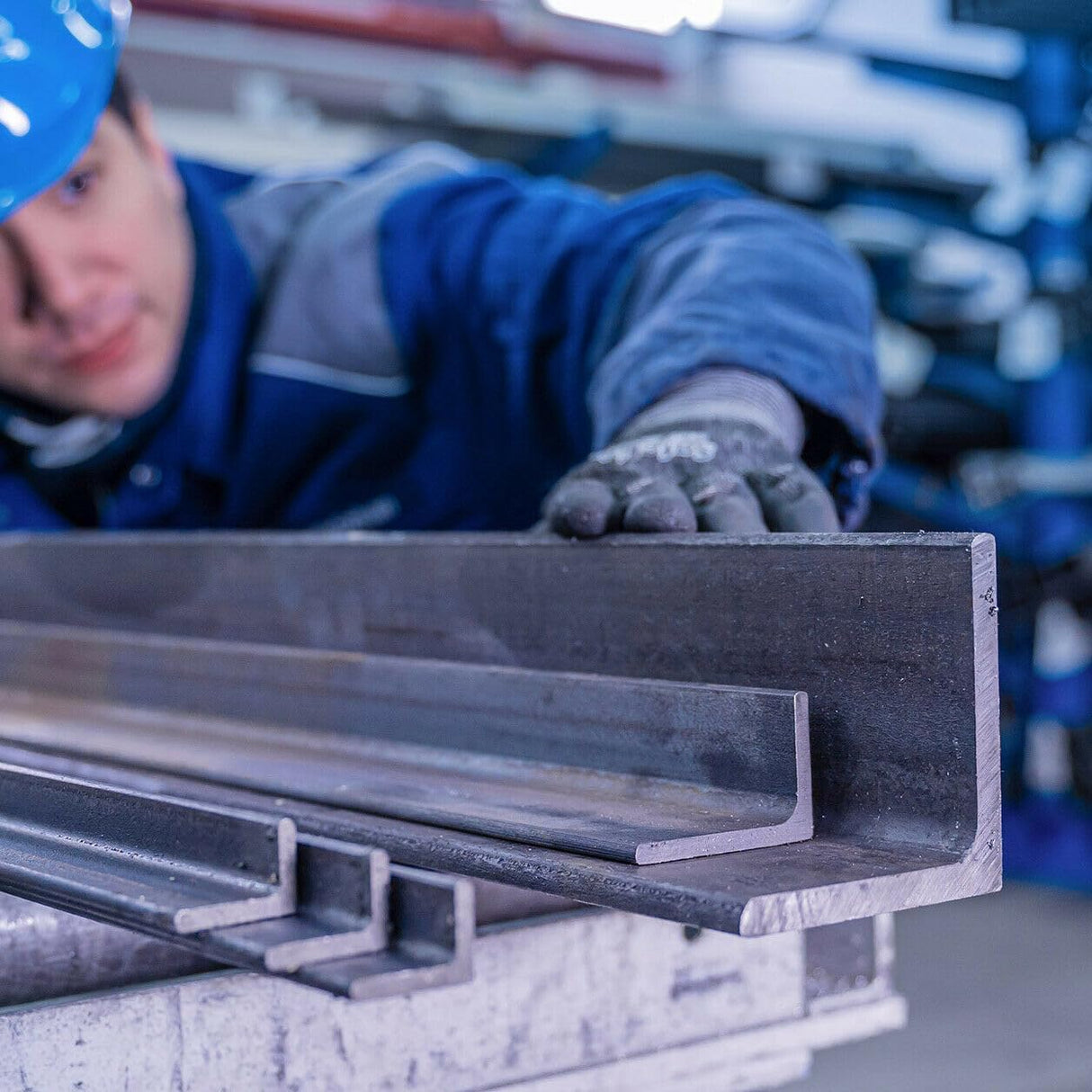 Kątowniki stalowe na metalowym stanowisku roboczym w tle pracownik sprawdza jakość