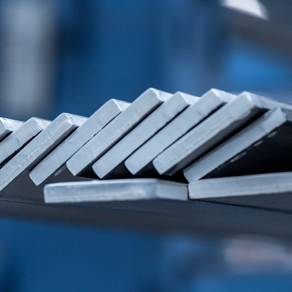 Rząd ułożonych pod kątem płaskowników nierdzewnych na tle hali